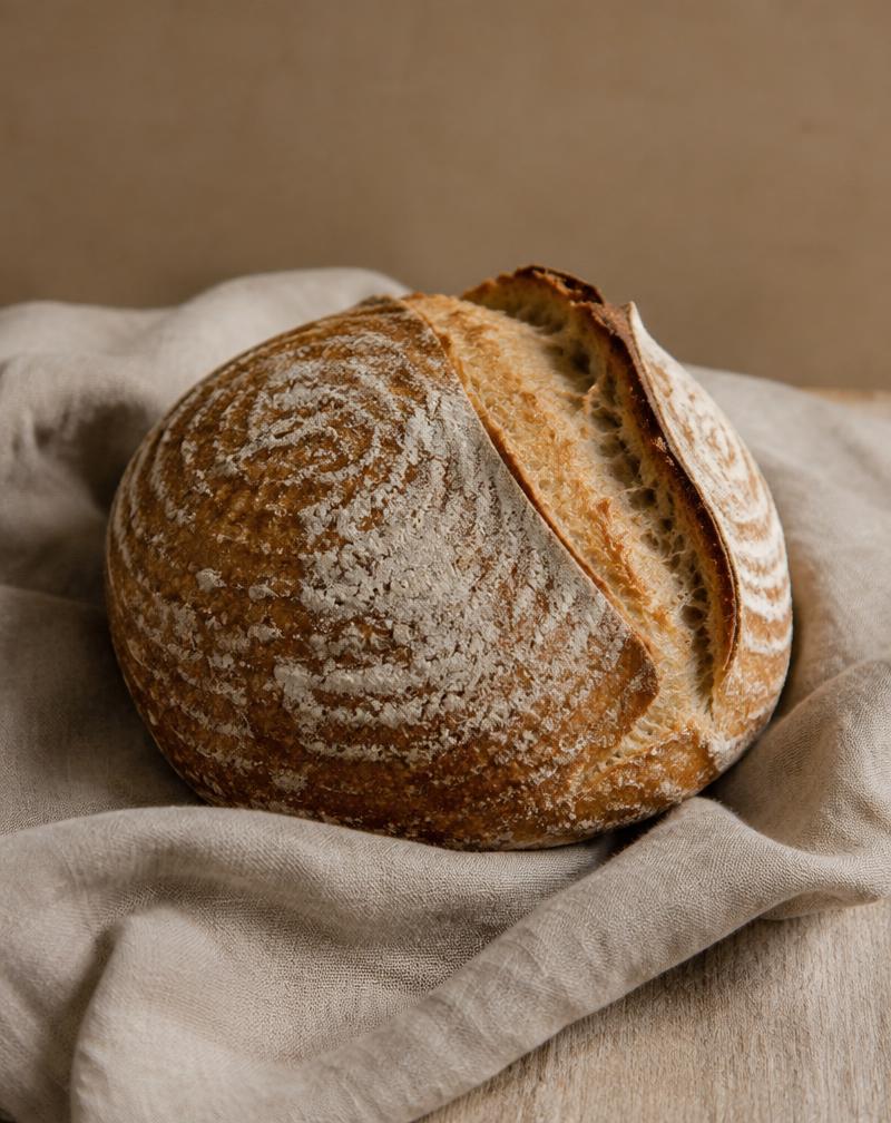 Rond zuurdesembrood met open korst op linnen doek